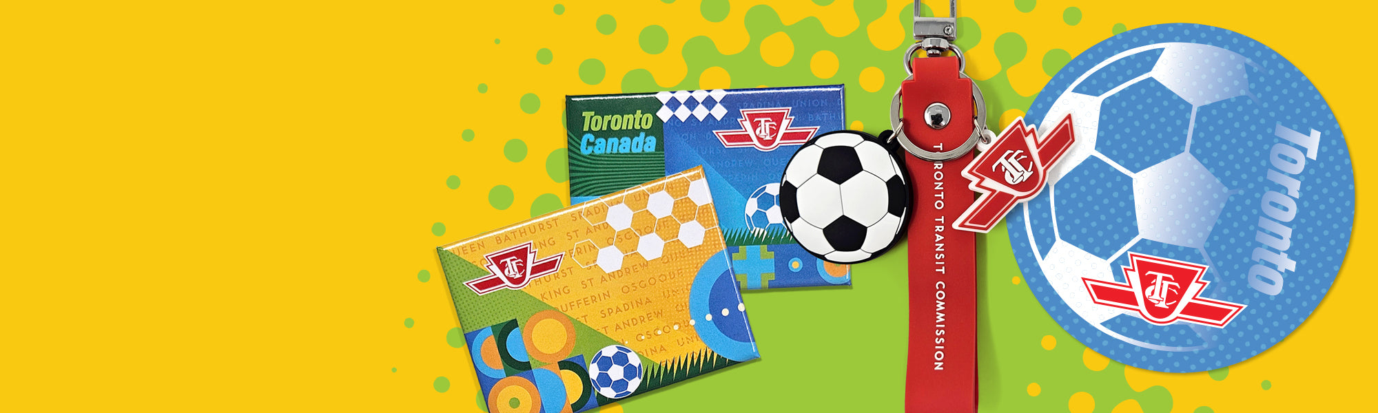 Toronto FC merchandise set featuring a blue soccer ball, a black and white soccer ball, a red and white keychain, and two cards on a bright yellow background with green spots.